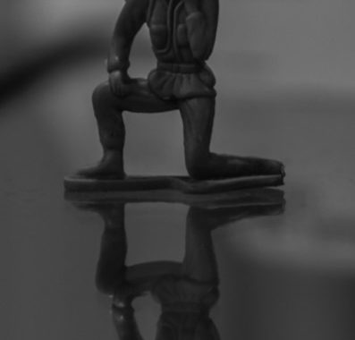 A black and white photo of a toy solider on a table