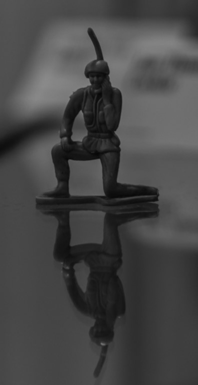 A black and white photo of a toy solider on a table